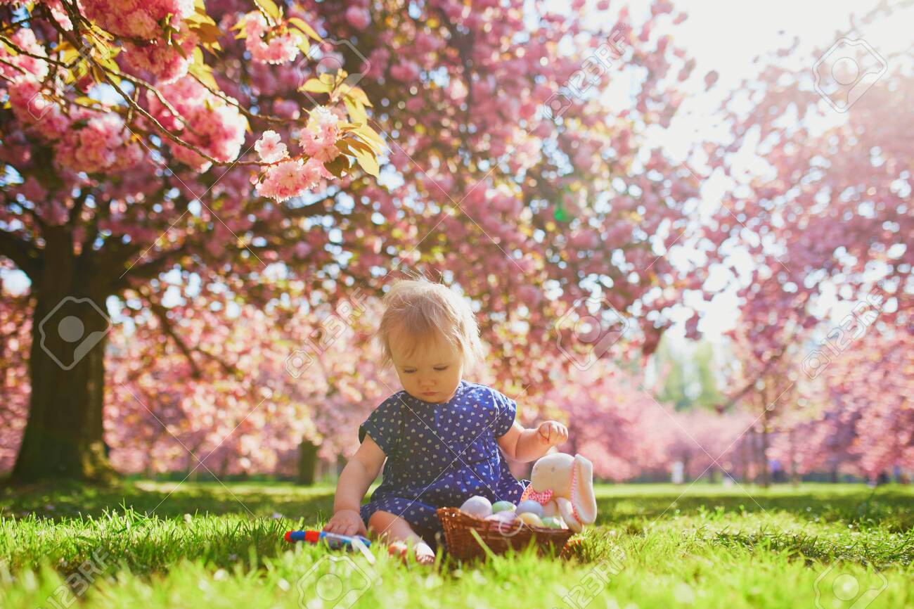 Cute Little One Year Old Girl Playing Egg Hunt On Easter Toddler Sitting On The Grass