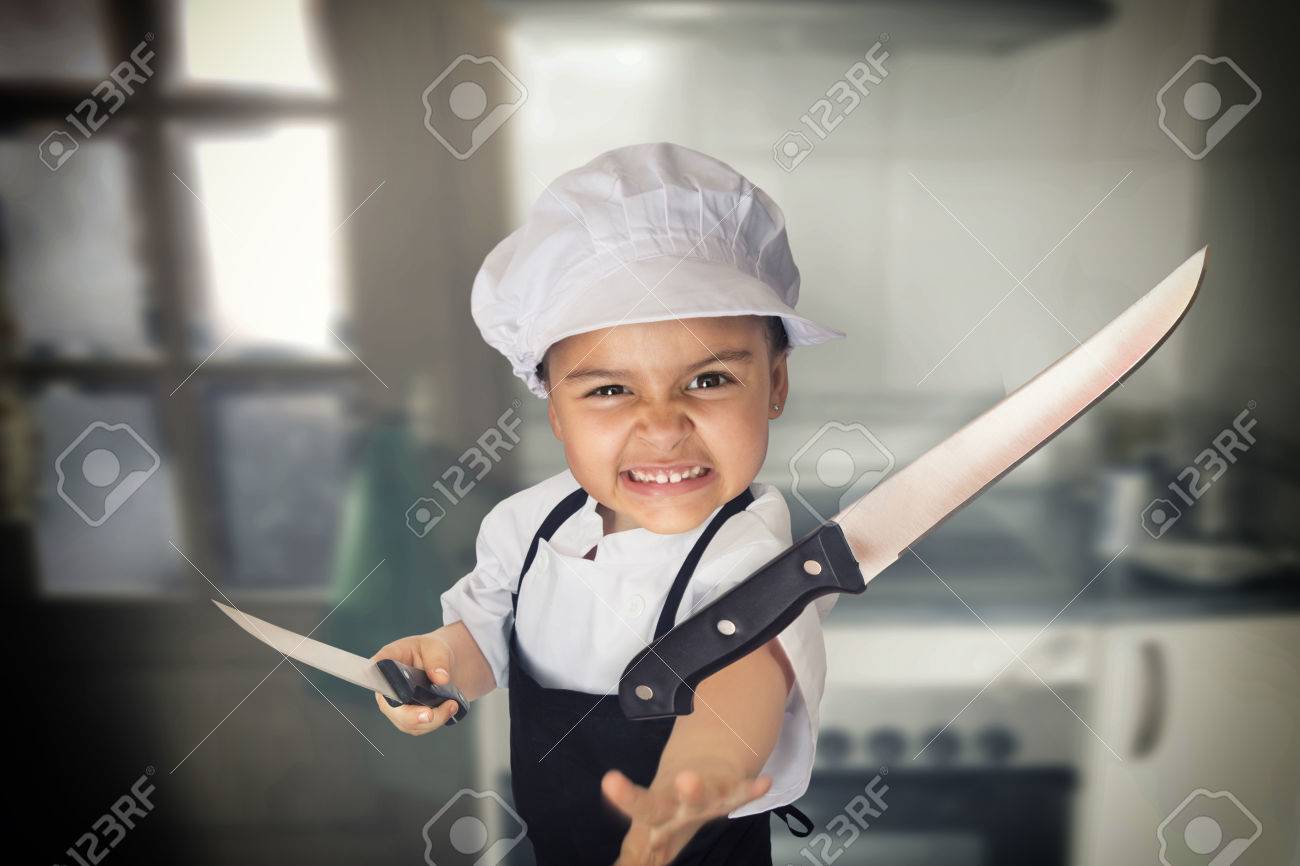ナイフを投げる料理人として服を着て 4 年間女の子の面白い肖像画 の写真素材 画像素材 Image