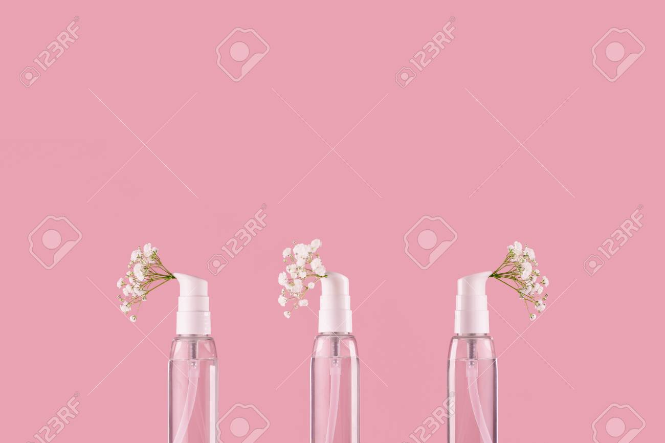 three bottle of perfume with spray scent of flowers on pink