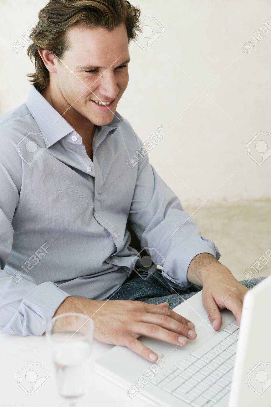 Young male looking content whilst working on laptop at home - 7597379 Young male looking content whilst working on laptop at home - 7597379