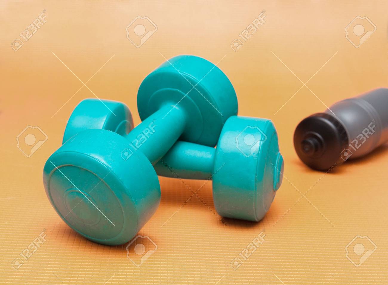青いフィットネス ダンベルとオレンジ色の背景に灰色の水のボトル の写真素材 画像素材 Image