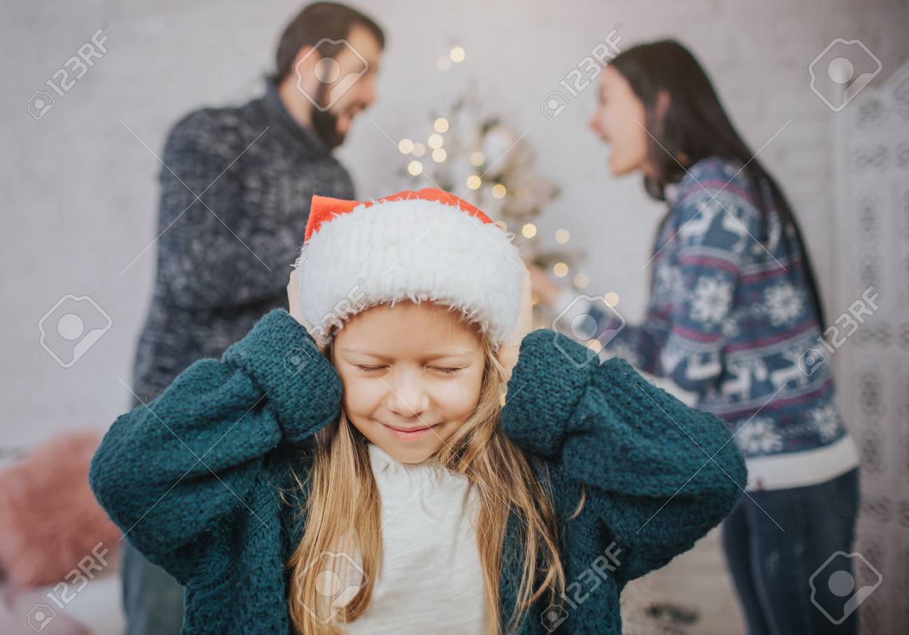 Sad, desperate little girl during parents quarrel. Clog the ears.. Family quarrel on the eve of Christmas. - 92412444 Sad, desperate little girl during parents quarrel. Clog the ears.. Family quarrel on the eve of Christmas. - 92412444