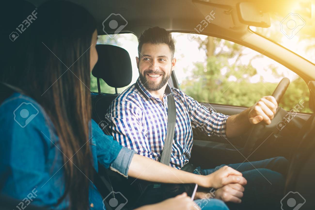 Careful driving. Beautiful young couple sitting on the front passenger seats and smiling while handsome man driving a car - 92879647 Careful driving. Beautiful young couple sitting on the front passenger seats and smiling while handsome man driving a car - 92879647