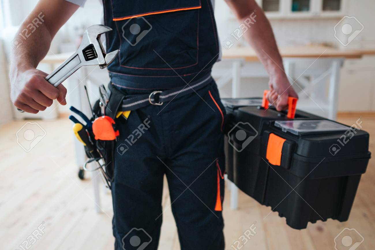 Cut view of handyman holding tool box and wrench in hands. He stand in kitchen. Guy wear special uniform. Daylight - 118701901 Cut view of handyman holding tool box and wrench in hands. He stand in kitchen. Guy wear special uniform. Daylight - 118701901