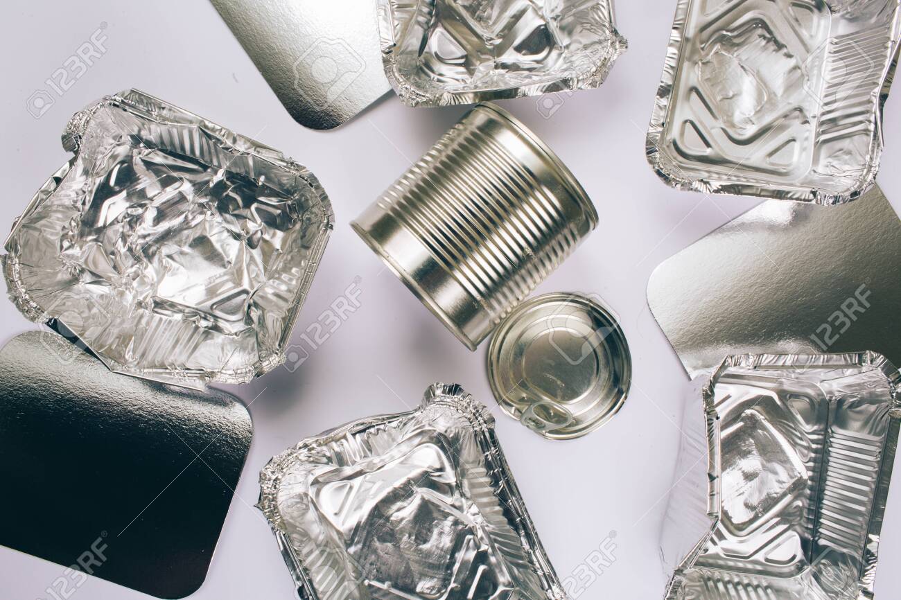 Plastic pollution concept. Foil silver container for food, silver cardboards and metal cans on white background, top view. Single-use plastic. New rules to reduce plastic waste, EU directive. We can no longer pollute our planet - 121637727 Plastic pollution concept. Foil silver container for food, silver cardboards and metal cans on white background, top view. Single-use plastic. New rules to reduce plastic waste, EU directive. We can no longer pollute our planet - 121637727