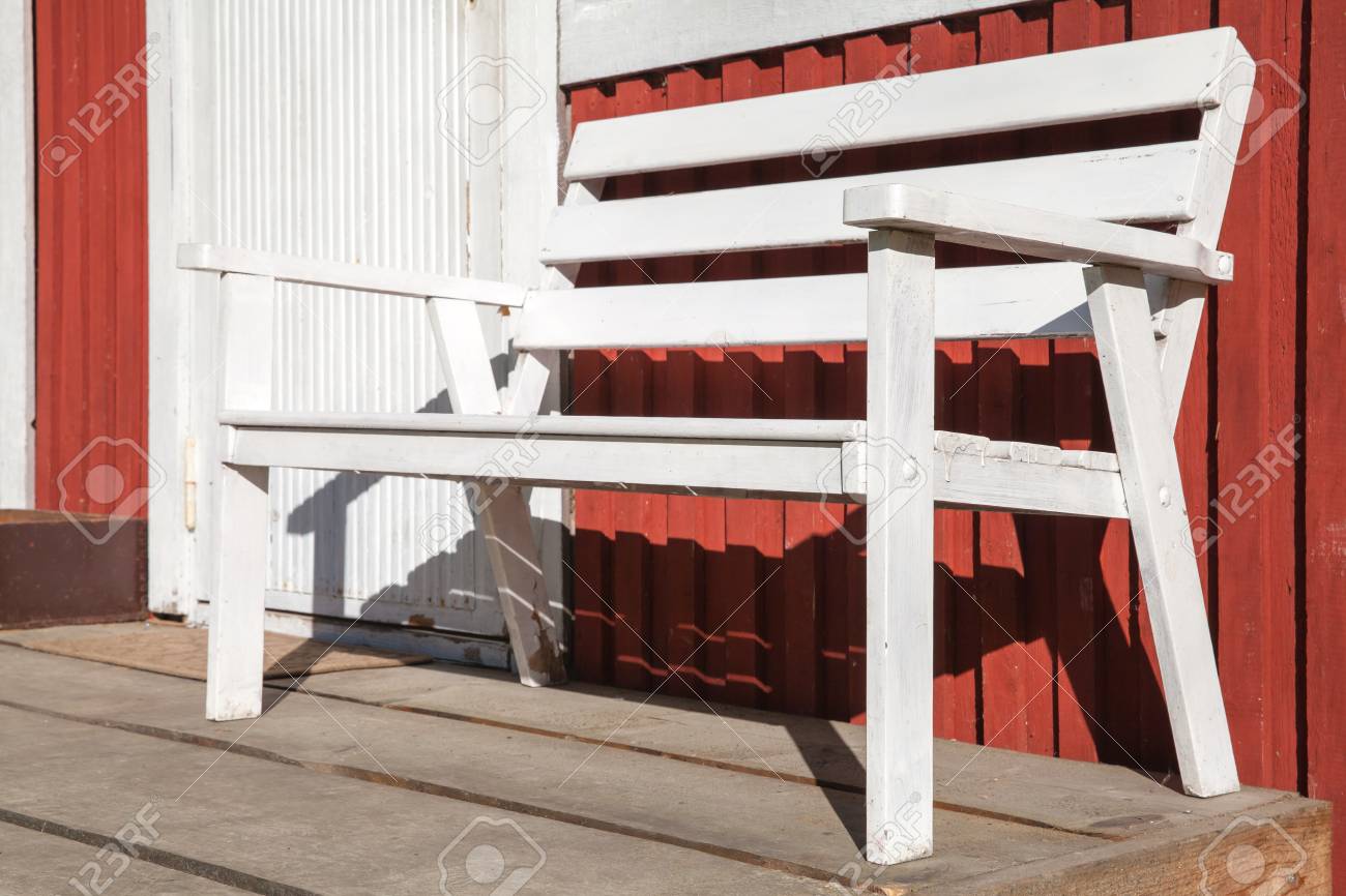 white wooden bench stands on terrace of scandinavian red wooden