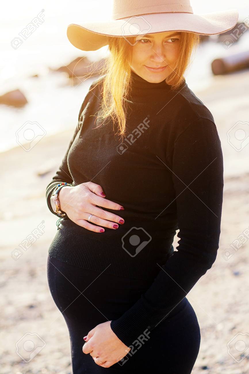 黒のタートルネック 黒のタイト スカート 秋の日の穏やかな海に対するポーズ古典的なベージュの帽子の美しい若い妊婦のクローズ アップ の写真素材 画像素材 Image 0090