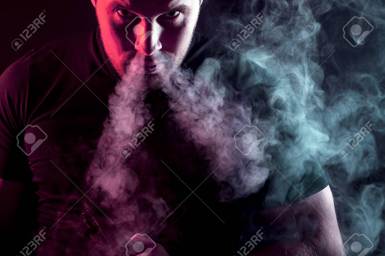 黒いtシャツを着た若いスタイリッシュな男性喫煙者は 暗い孤立した背景の蒸気から大きな煙の雲を鼻から見つめ 吐き出す の写真素材 画像素材 Image 93385060