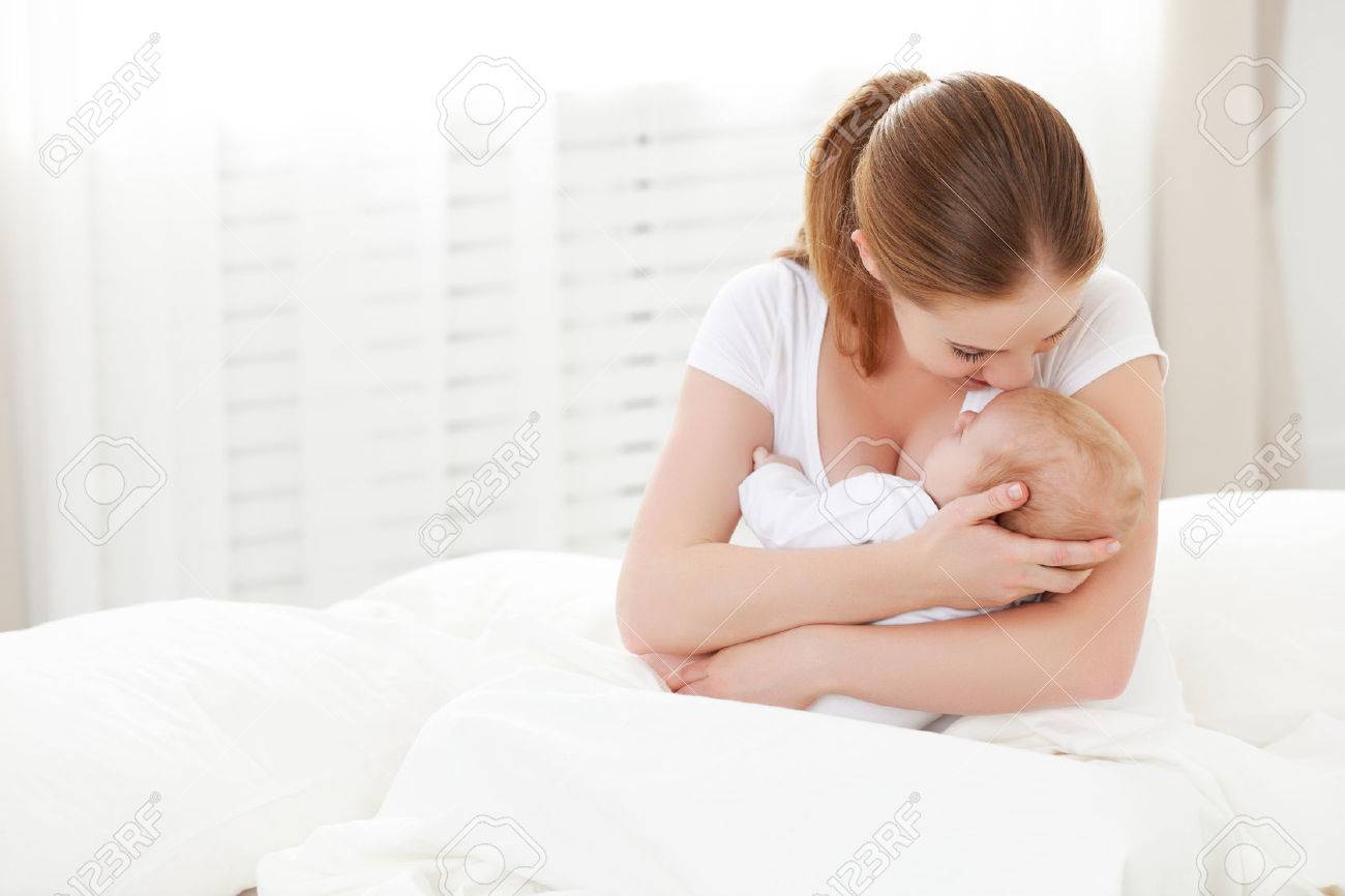 happy family newborn baby in an embrace his mother in a white bed - 50841356 happy family newborn baby in an embrace his mother in a white bed - 50841356