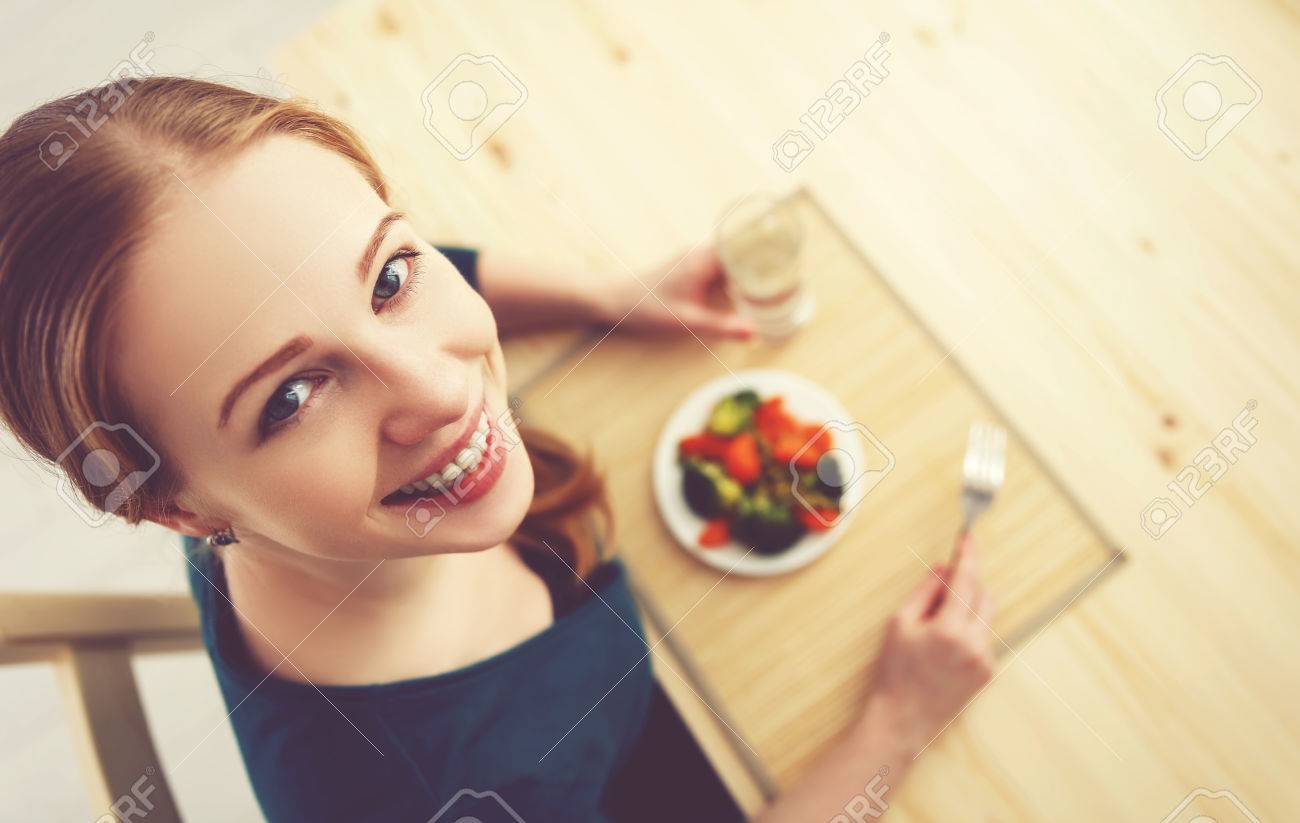 young healthy woman eats vegetables at home in the kitchen summer - 51917596 young healthy woman eats vegetables at home in the kitchen summer - 51917596
