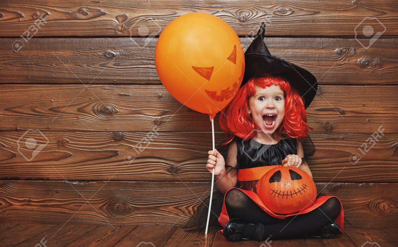 funny child girl in witch costume for Halloween with pumpkin Jack and orange balloon on a dark wooden background - 63077053 funny child girl in witch costume for Halloween with pumpkin Jack and orange balloon on a dark wooden background - 63077053