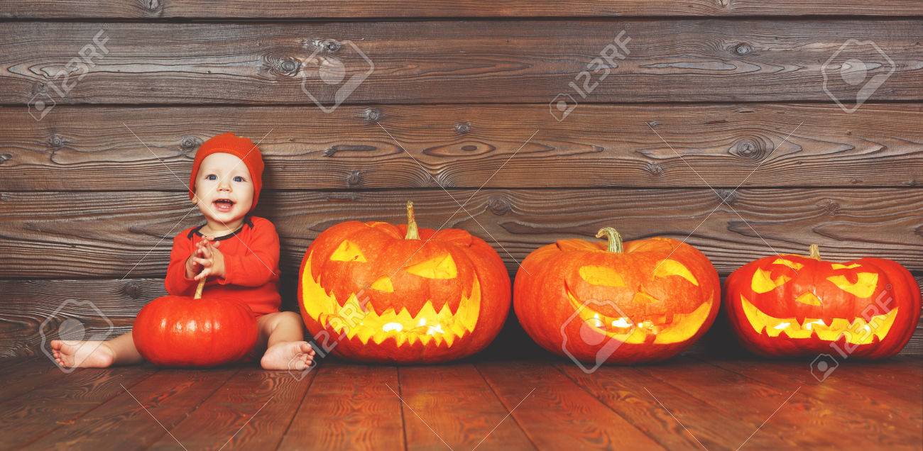 Happy Baby In Costume For Halloween With Pumpkins With Burning Eyes On Wooden Background Stock Photo Picture And Royalty Free Image Image
