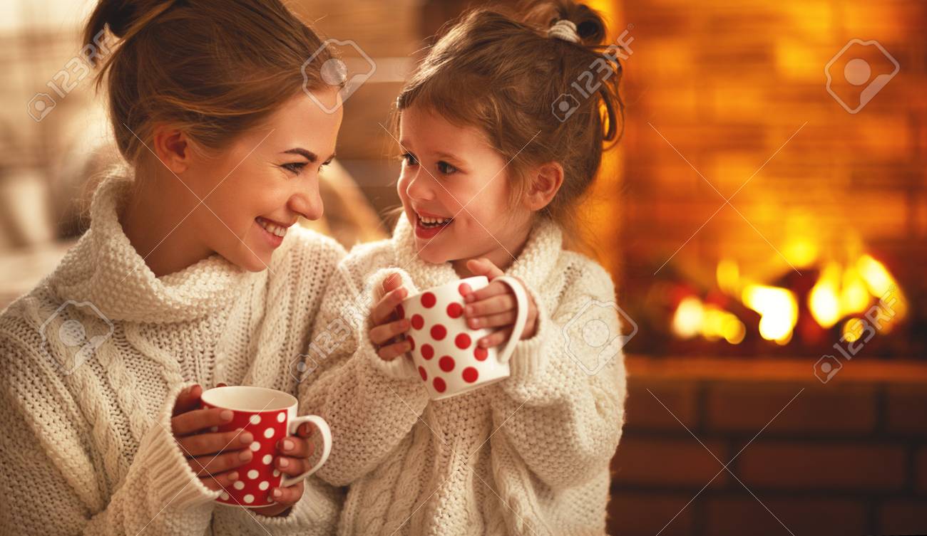 family mother and child daughter drinking tea and laughing on winter evening by fireplace - 93868325 family mother and child daughter drinking tea and laughing on winter evening by fireplace - 93868325
