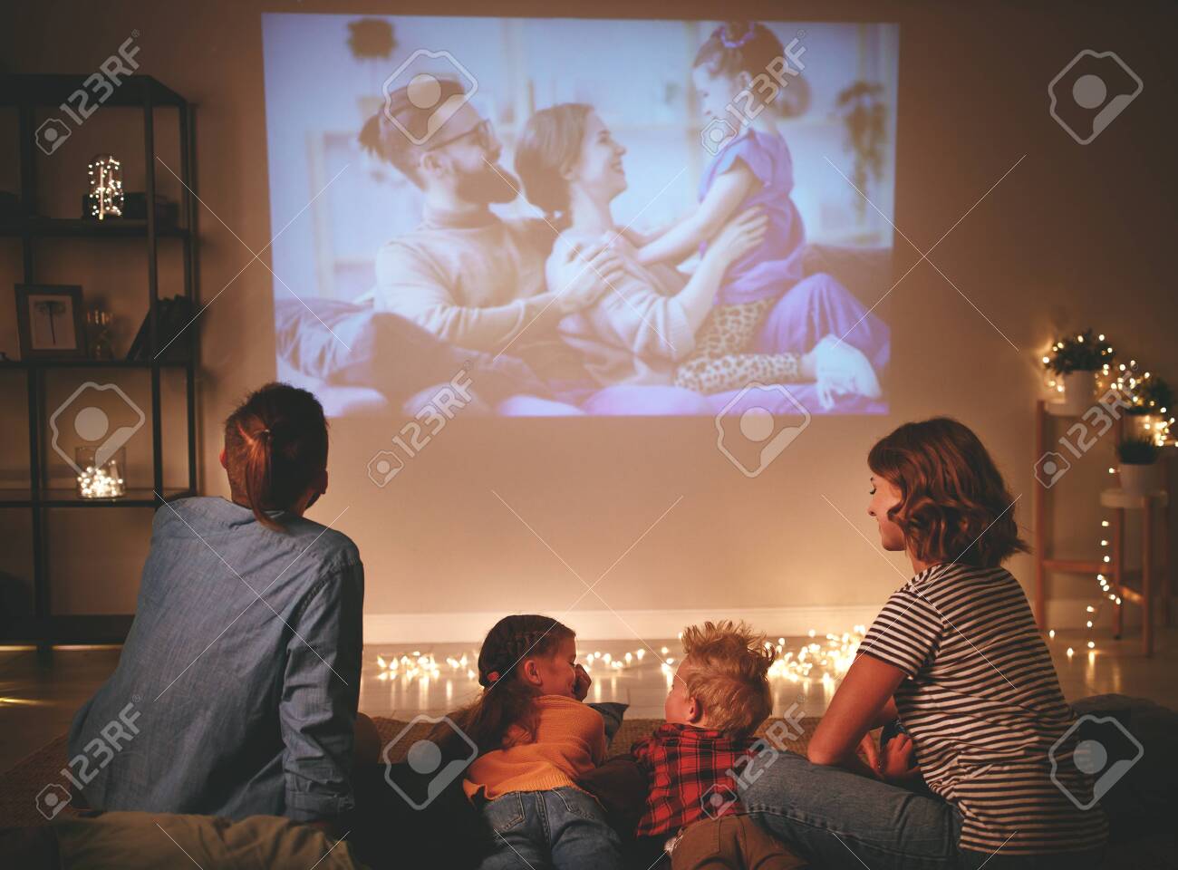 family mother father and children watching projector, TV, movies with popcorn in the evening at home - 130478057 family mother father and children watching projector, TV, movies with popcorn in the evening at home - 130478057
