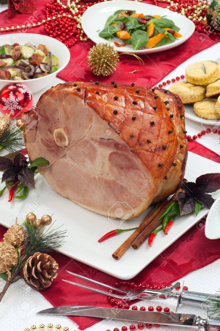 Roasted spiced ham on holiday dinning table, garnished with cloves, cinnamon sticks, hot chili pepper, and purple basil Side dishes and Christmas ornaments around - 16663873 Roasted spiced ham on holiday dinning table, garnished with cloves, cinnamon sticks, hot chili pepper, and purple basil Side dishes and Christmas ornaments around - 16663873