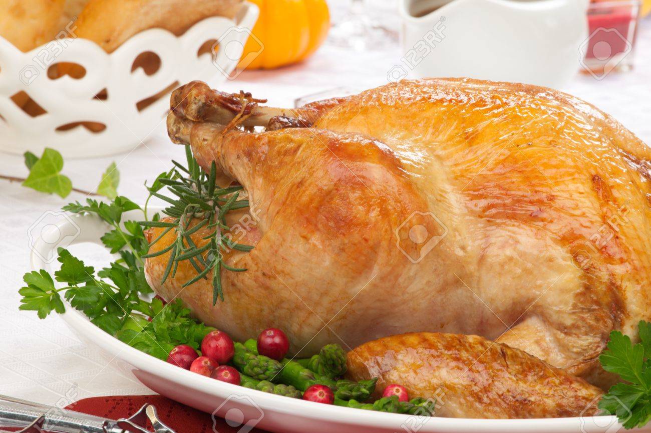 Garnished roasted turkey on fall festival decorated table with horn of plenty and red wine - 20705218 Garnished roasted turkey on fall festival decorated table with horn of plenty and red wine - 20705218