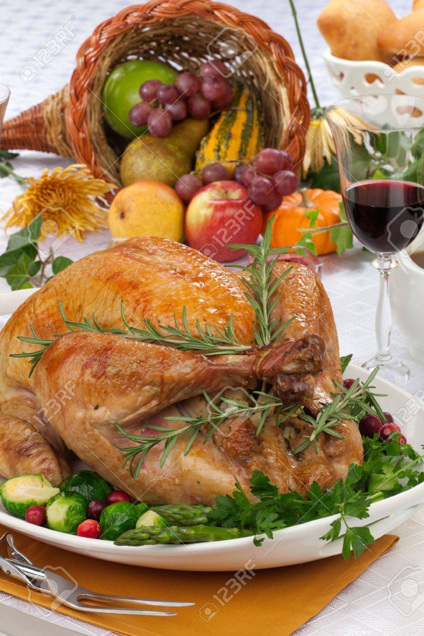 Garnished roasted turkey on fall festival decorated table with horn of plenty and red wine - 21565913 Garnished roasted turkey on fall festival decorated table with horn of plenty and red wine - 21565913