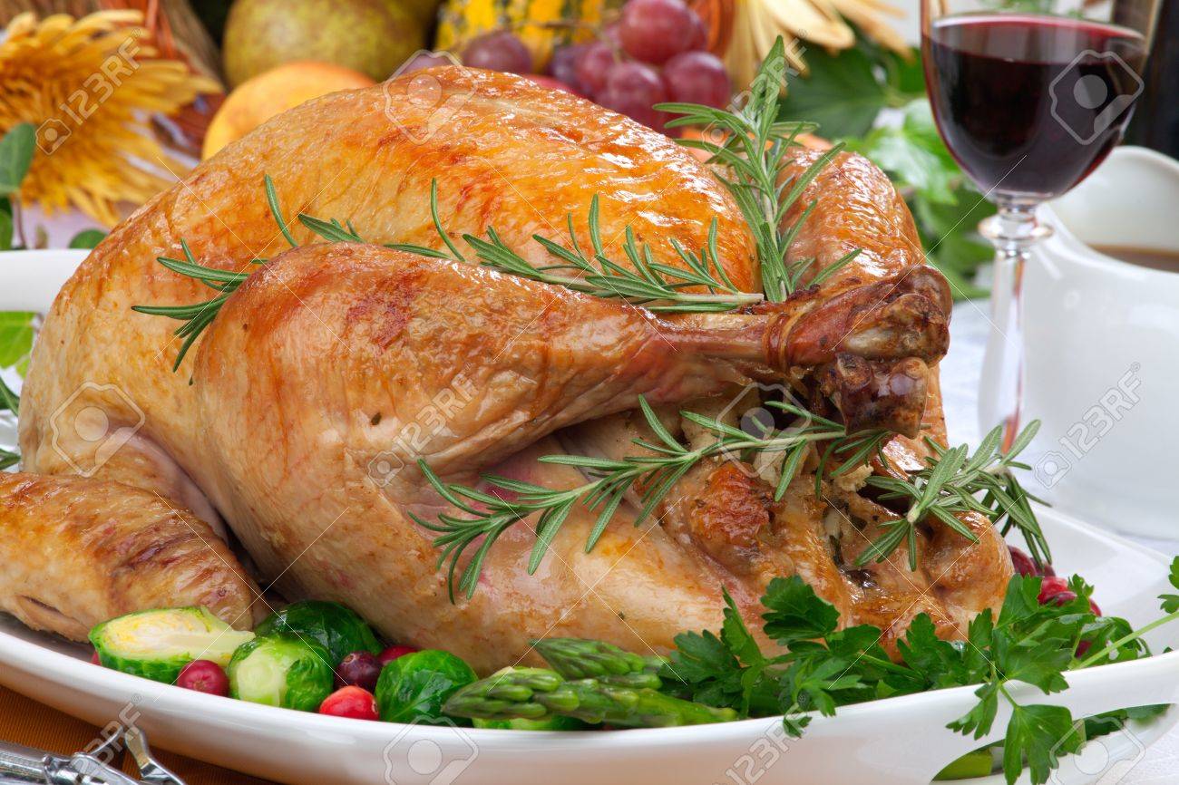 Garnished roasted turkey on fall festival decorated table with horn of plenty and red wine - 22026046 Garnished roasted turkey on fall festival decorated table with horn of plenty and red wine - 22026046