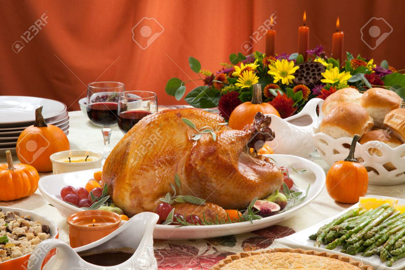 Roasted turkey on a server tray garnished with fresh figs, grape, kumquat, and herbs on fall harvest table. Red wine, side dishes, pie, and gravy. Decoraded with mini pumpkins, candels, and flowers. - 32816621 Roasted turkey on a server tray garnished with fresh figs, grape, kumquat, and herbs on fall harvest table. Red wine, side dishes, pie, and gravy. Decoraded with mini pumpkins, candels, and flowers. - 32816621