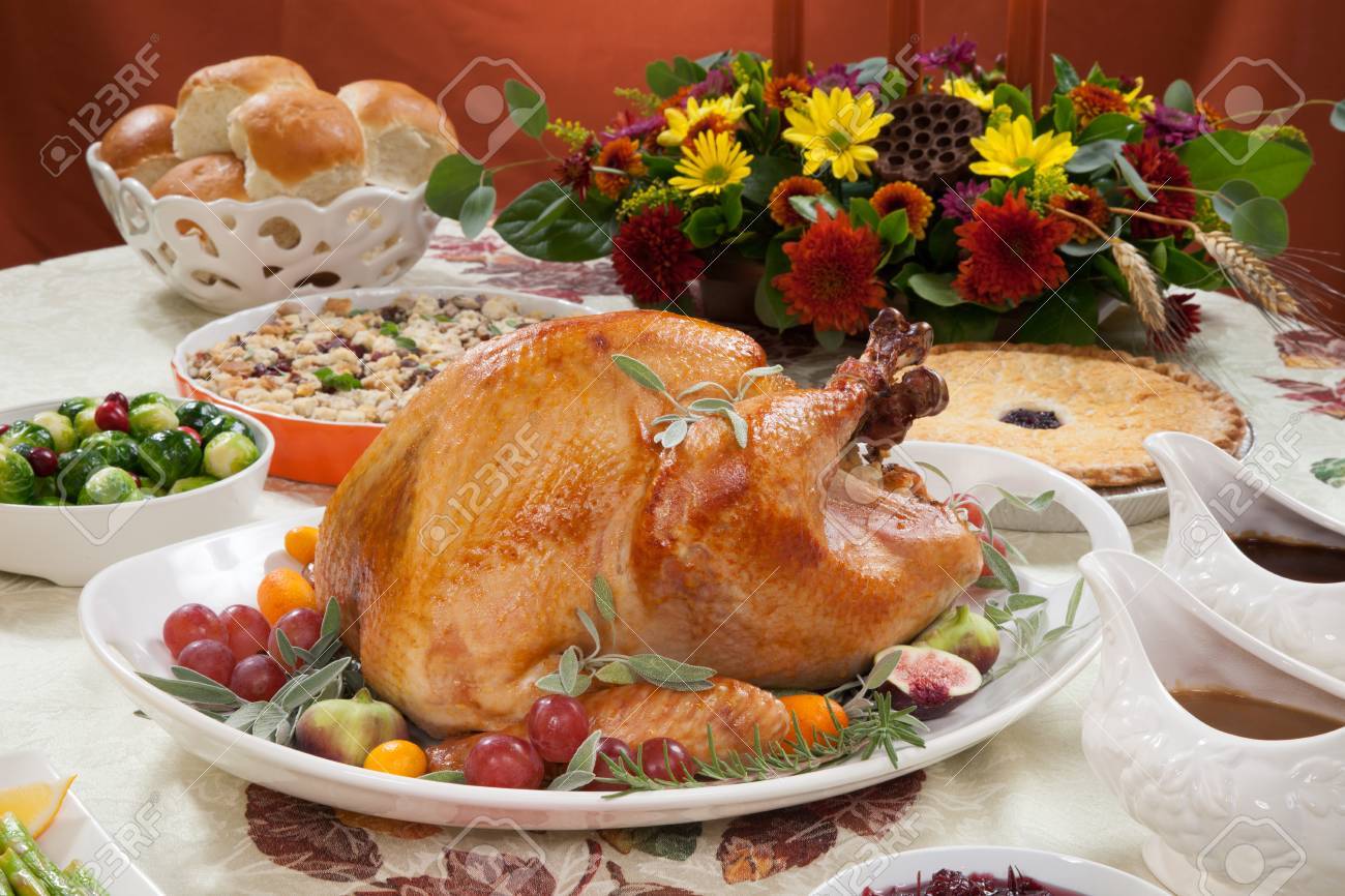 Roasted turkey on a server tray garnished with fresh figs grape kumquat and herbs on fall harvest table. Red wine side dishes pie and gravy. Decoraded with mini pumpkins candels and flowers. - 41926300 Roasted turkey on a server tray garnished with fresh figs grape kumquat and herbs on fall harvest table. Red wine side dishes pie and gravy. Decoraded with mini pumpkins candels and flowers. - 41926300