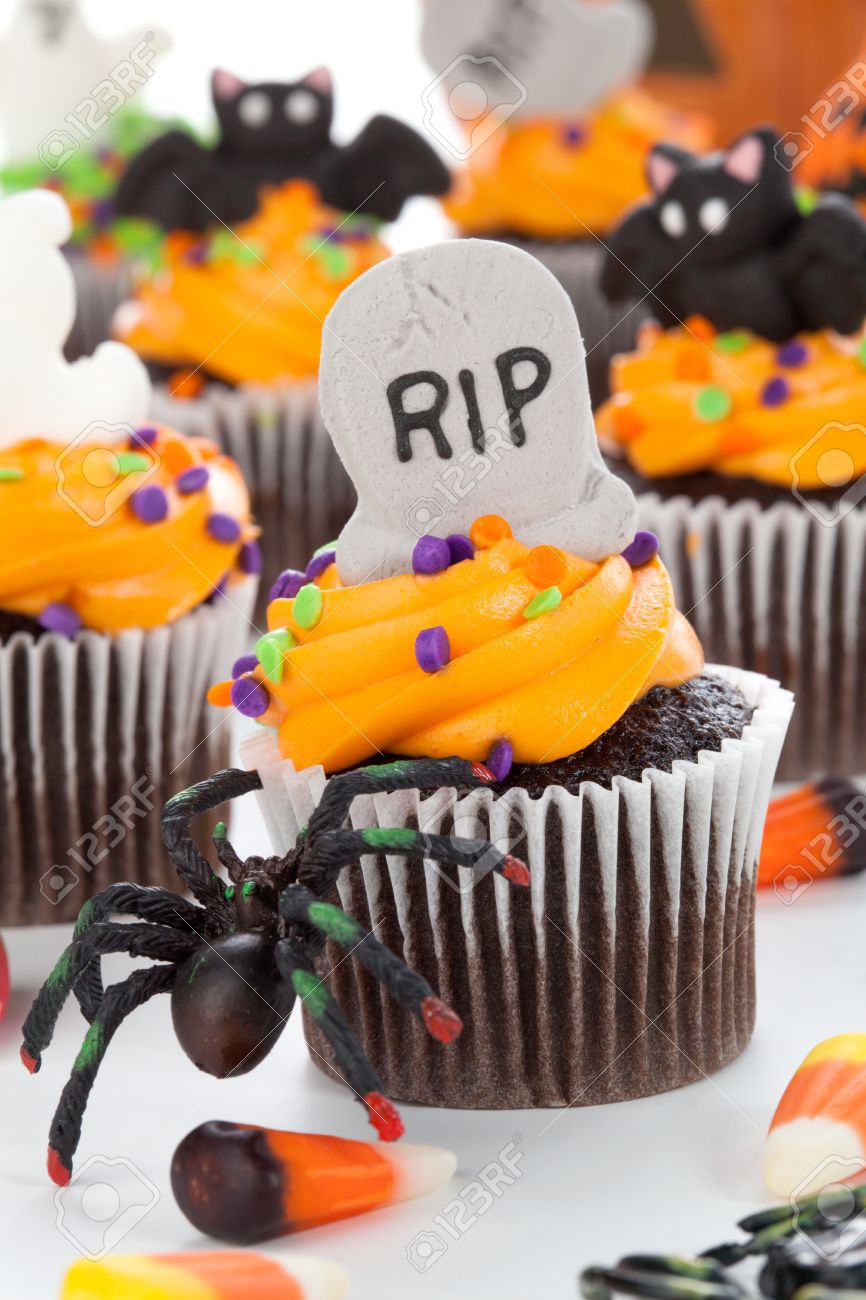 halloween cupcake with rip ghost and bat decorations surrounded by halloween cupcakes corn
