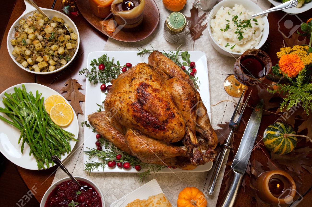 Roasted turkey garnished with cranberries on a rustic style table decoraded with pumpkins, gourds, asparagus, brussel sprouts, baked vegetables, pie, flowers, and candles. - 46860336 Roasted turkey garnished with cranberries on a rustic style table decoraded with pumpkins, gourds, asparagus, brussel sprouts, baked vegetables, pie, flowers, and candles. - 46860336