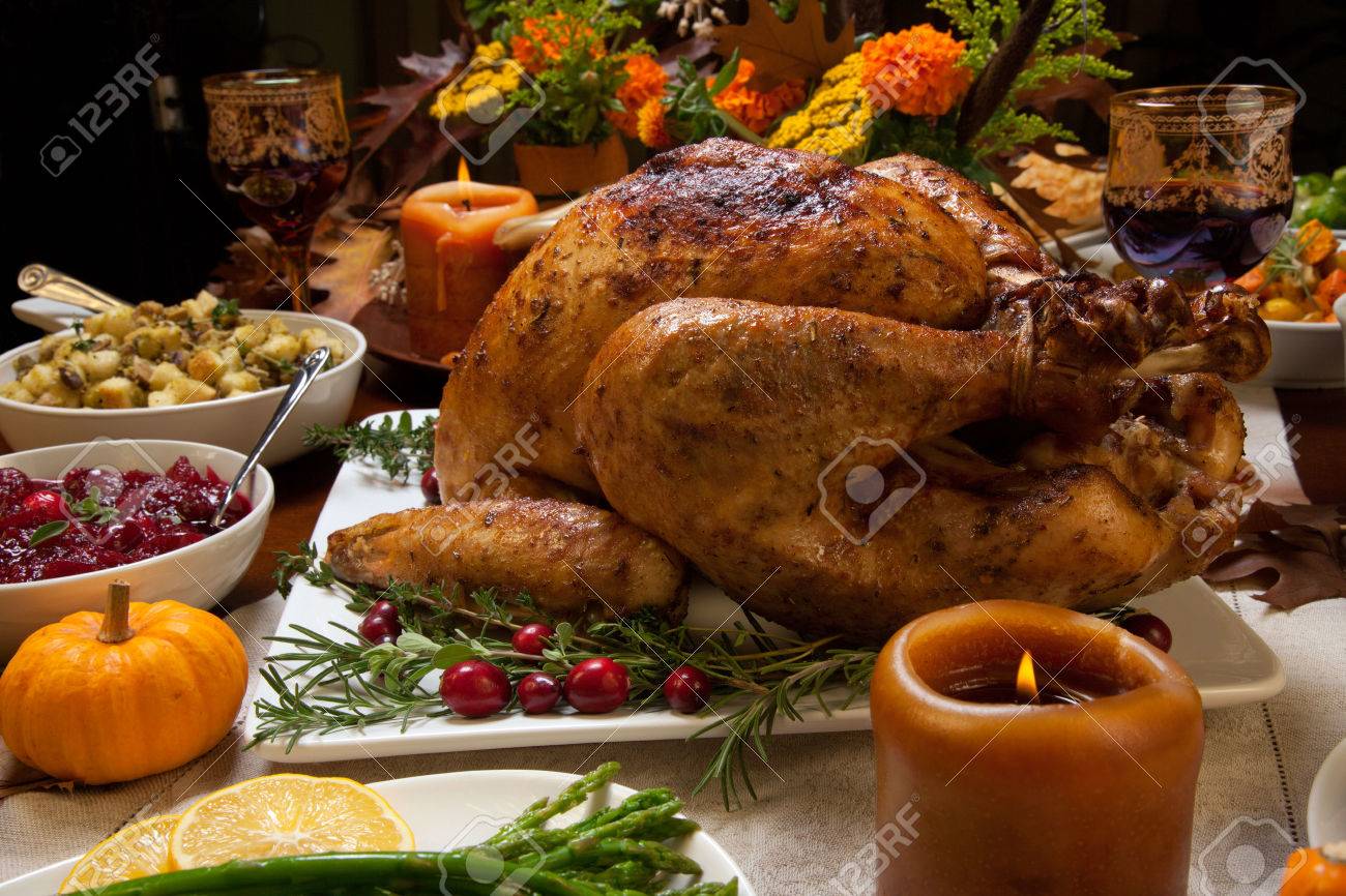 Roasted turkey garnished with cranberries on a rustic style table decoraded with pumpkins, gourds, asparagus, brussel sprouts, baked vegetables, pie, flowers, and candles. - 48887554 Roasted turkey garnished with cranberries on a rustic style table decoraded with pumpkins, gourds, asparagus, brussel sprouts, baked vegetables, pie, flowers, and candles. - 48887554