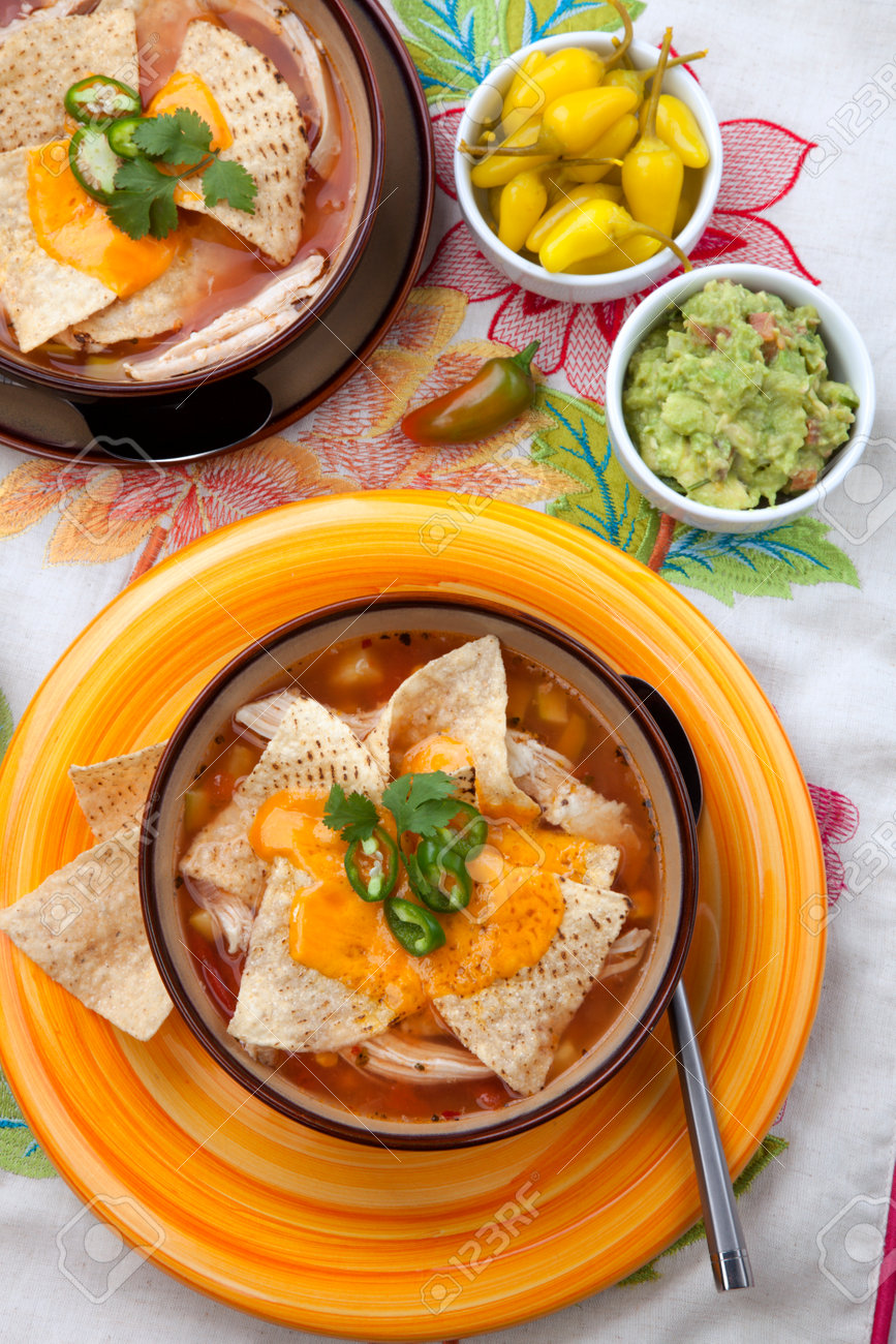 Closeup of two bowls of hot delicious spicy chicken nacho soup, garnished with melted cheese, jalapeno pepper, and fresh cilantro. Salsa, guacamole, and marinated hot pepper. - 162557494 Closeup of two bowls of hot delicious spicy chicken nacho soup, garnished with melted cheese, jalapeno pepper, and fresh cilantro. Salsa, guacamole, and marinated hot pepper. - 162557494