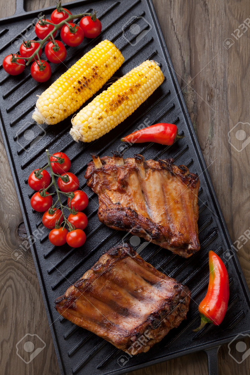 Grilled pork ribs on griddle with chili pepper, cherry tomatoes, and grilled corn - 162557501 Grilled pork ribs on griddle with chili pepper, cherry tomatoes, and grilled corn - 162557501