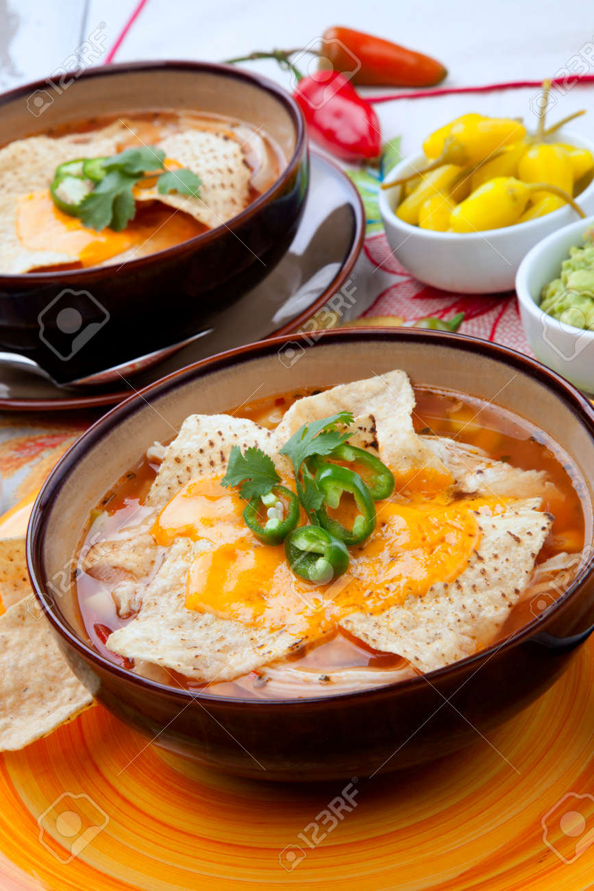 Closeup of two bowls of hot delicious spicy chicken nacho soup, garnished with melted cheese, jalapeno pepper, and fresh cilantro. Salsa, guacamole, and marinated hot pepper. - 166621252 Closeup of two bowls of hot delicious spicy chicken nacho soup, garnished with melted cheese, jalapeno pepper, and fresh cilantro. Salsa, guacamole, and marinated hot pepper. - 166621252