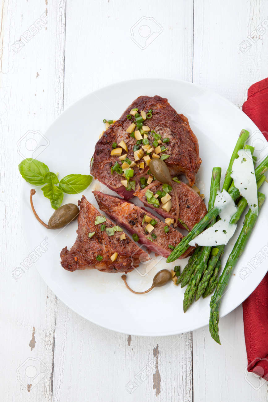 Grilled steak dressed with olive tapenade garnished with asparagus and cheese. - 171546621 Grilled steak dressed with olive tapenade garnished with asparagus and cheese. - 171546621