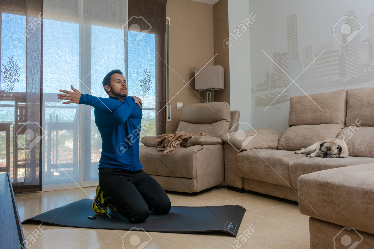 Latin man, doing a workout in his living room, does sit-ups, stretches and squats - 162578105 Latin man, doing a workout in his living room, does sit-ups, stretches and squats - 162578105