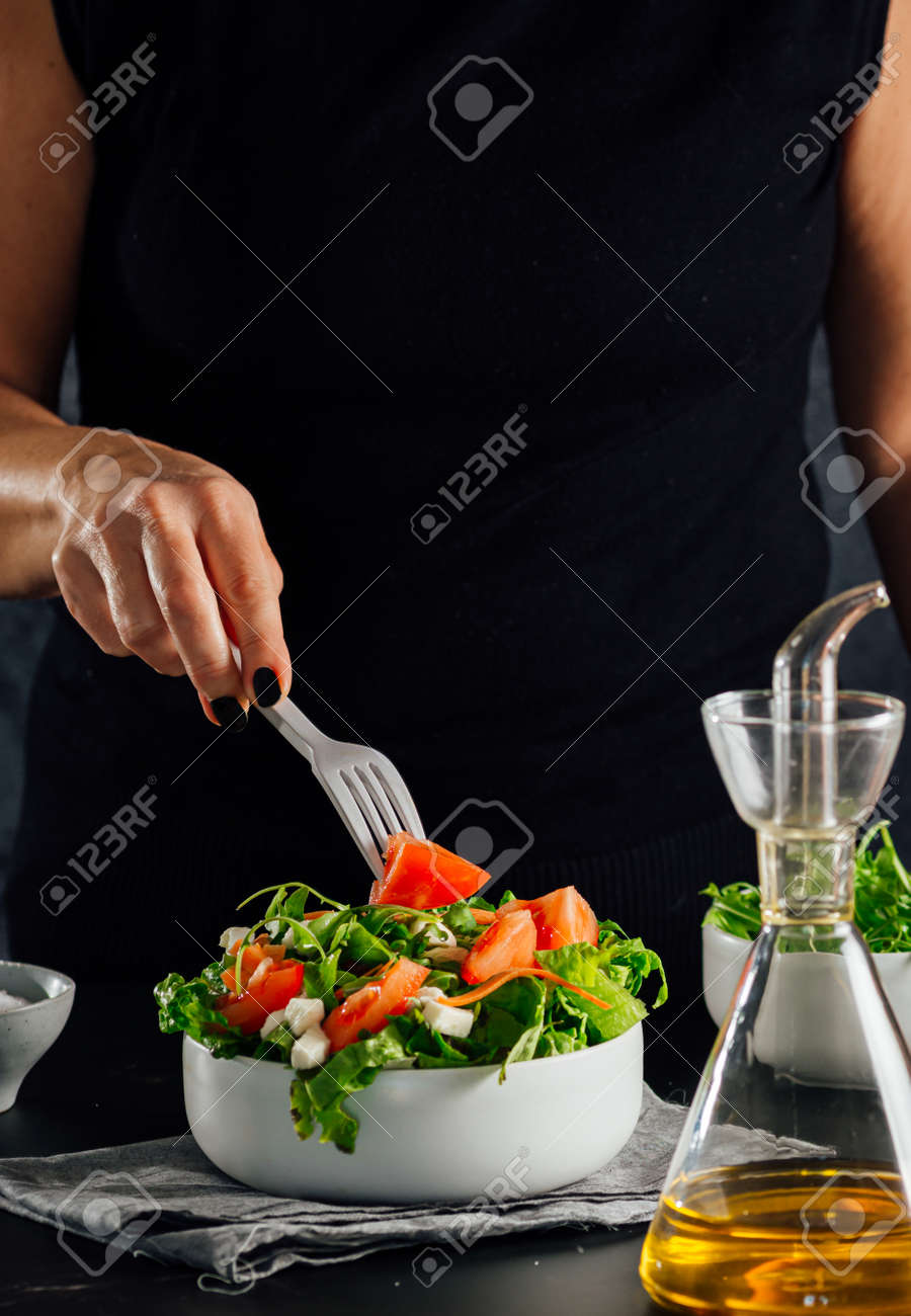 Woman preparing a salad with tomatoes, lettuce, olive oil and salt Concept of healthy diet - 165273826 Woman preparing a salad with tomatoes, lettuce, olive oil and salt Concept of healthy diet - 165273826