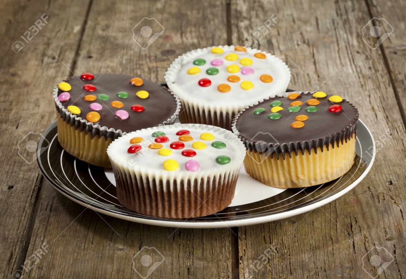 Quatre Petits Gateaux Avec Glacage Au Chocolat Noir Et Blanc Et Smarties Sur Une Plaque Banque D Images Et Photos Libres De Droits Image