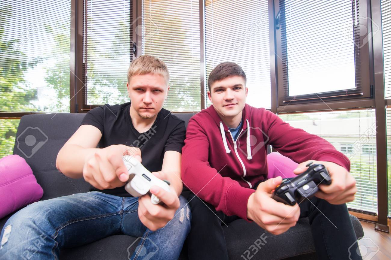 Amis Et Jeux Video Deux Beaux Jeunes Hommes Jouant A Des Jeux Video Tout En Etant Assis Sur Le Canape Banque D Images Et Photos Libres De Droits Image 63671472