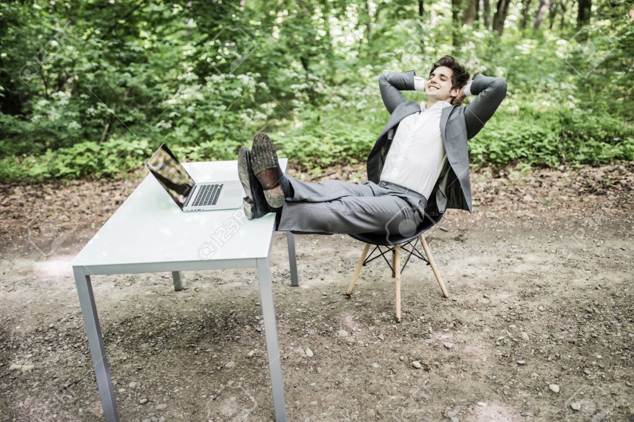 頭や緑豊かな公園で成功する仕事の後のオフィスの机の脚に頭を持つスーツを着た男でリラックスしたビジネス フリーランサーは 緑の森林を大いに後リラックスします の写真素材 画像素材 Image