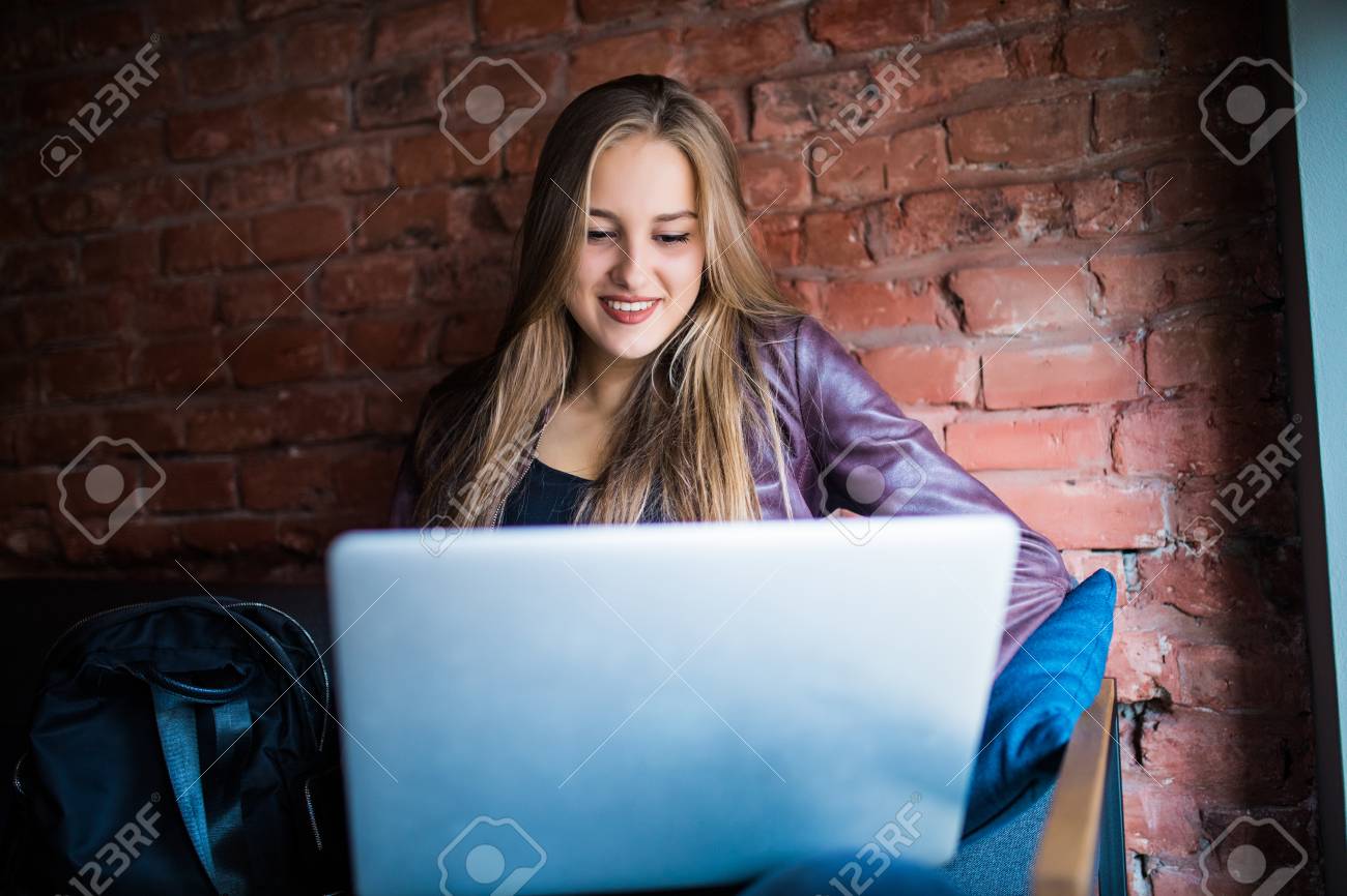 美しい若いフリーランスの女性がカフェのテーブルに座ってラップトップ コンピューターを使用して 幸せな笑顔の女の子のオンラインでの作業や勉強 ノートを使用しながら学習します フリーランスの仕事は 人々 のビジネス コンセプト の写真素材 画像素材 Image