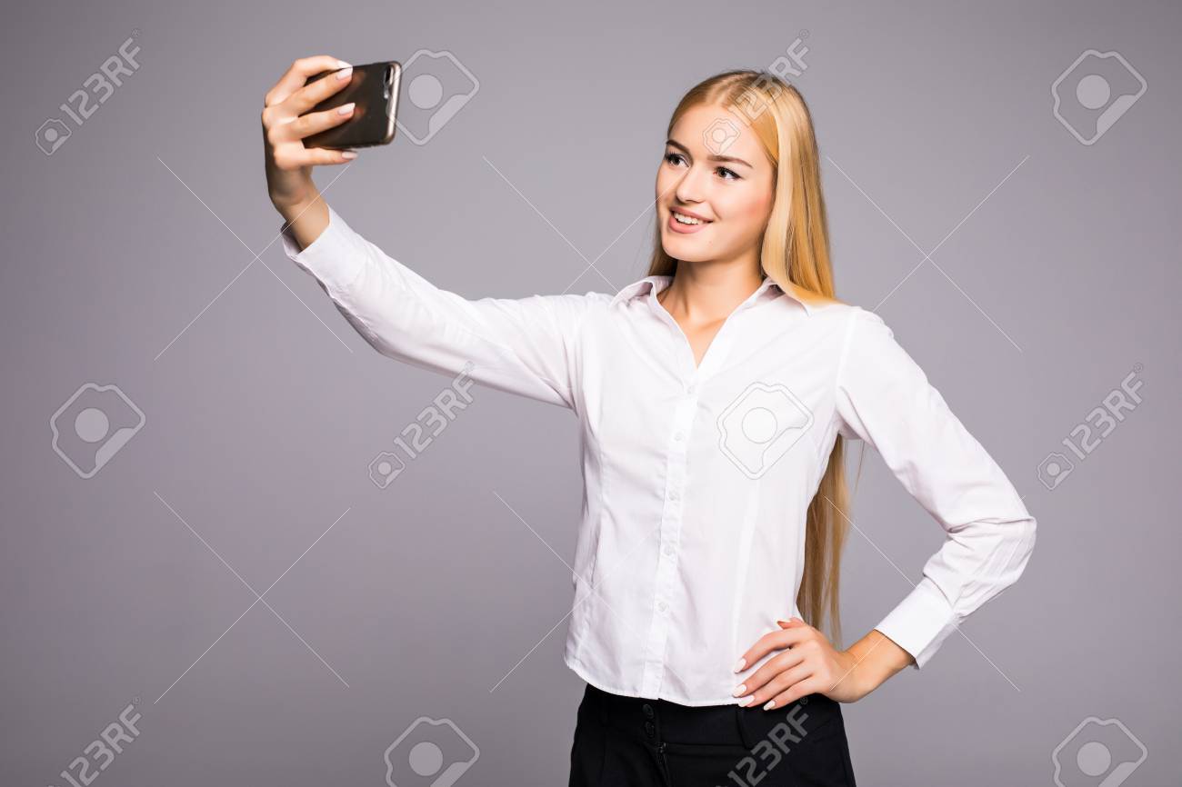 スマートフォンで自撮り写真を作る笑顔のビジネスウーマンは 灰色の背景の上に立って の写真素材 画像素材 Image スマートフォンで自撮り写真を作る笑顔のビジネスウーマンは 灰色の背景の上に立って の写真素材 画像素材 Image