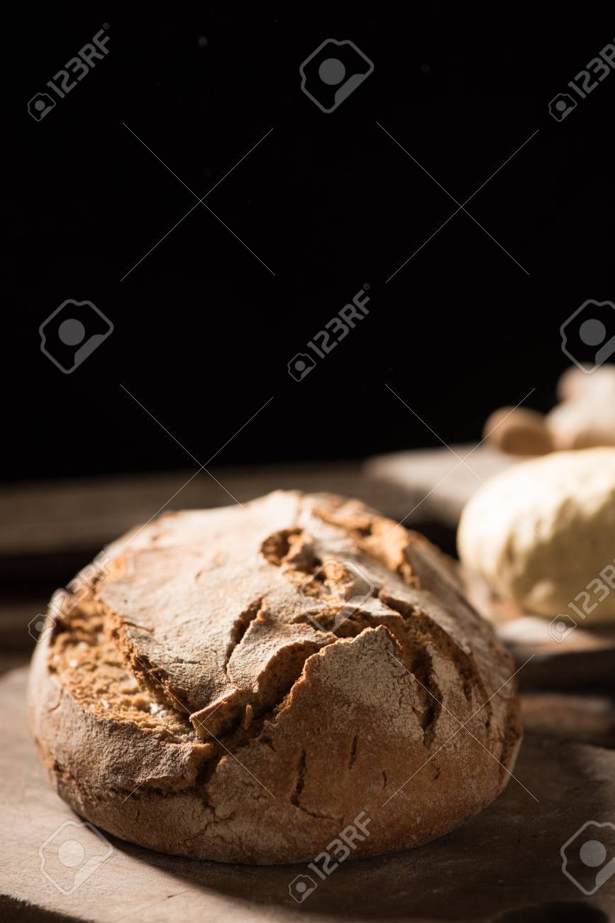 Freshly Baked Bread On Wooden Table On Dark Background Stock Photo