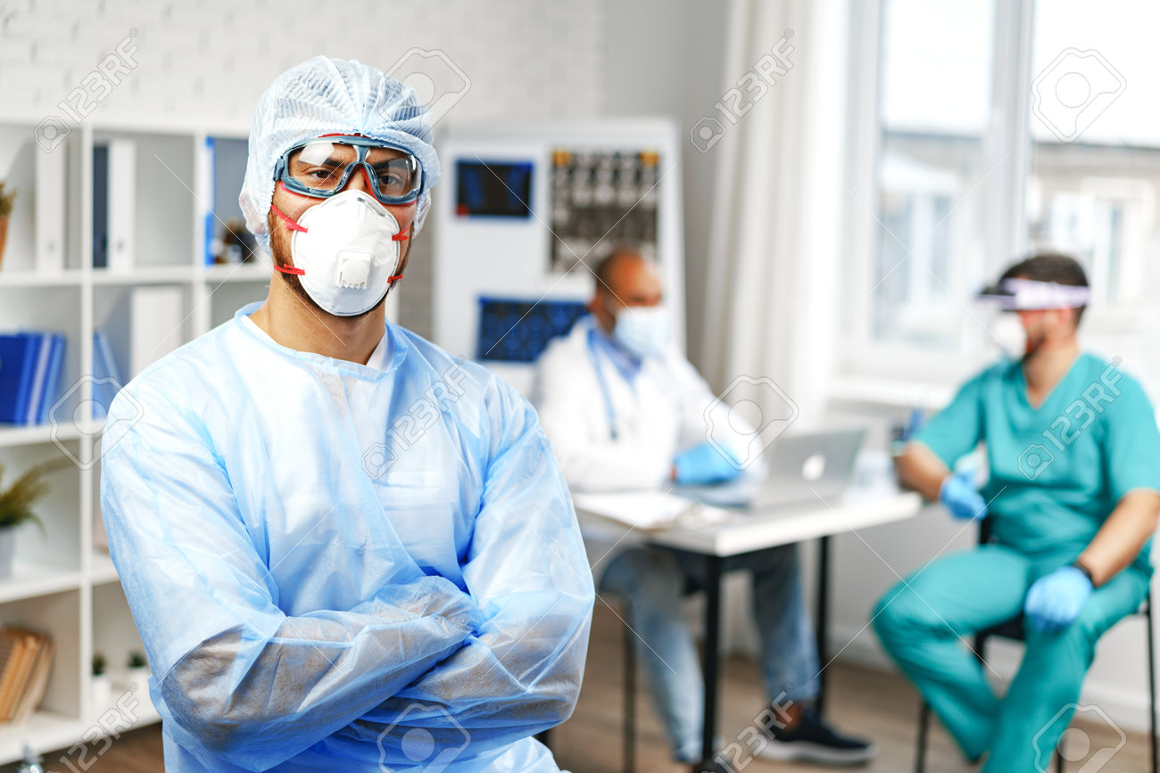 Male doctor in protective medical gown standing in hospital cabinet - 161749182 Male doctor in protective medical gown standing in hospital cabinet - 161749182