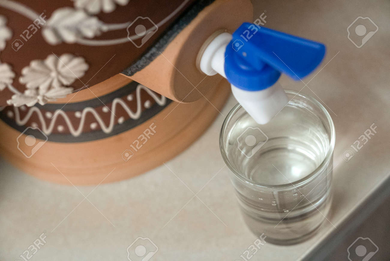 A glass of water from traditional water dispenser called Labu Sayong (water calabash) in Malay language. - 169597260 A glass of water from traditional water dispenser called Labu Sayong (water calabash) in Malay language. - 169597260
