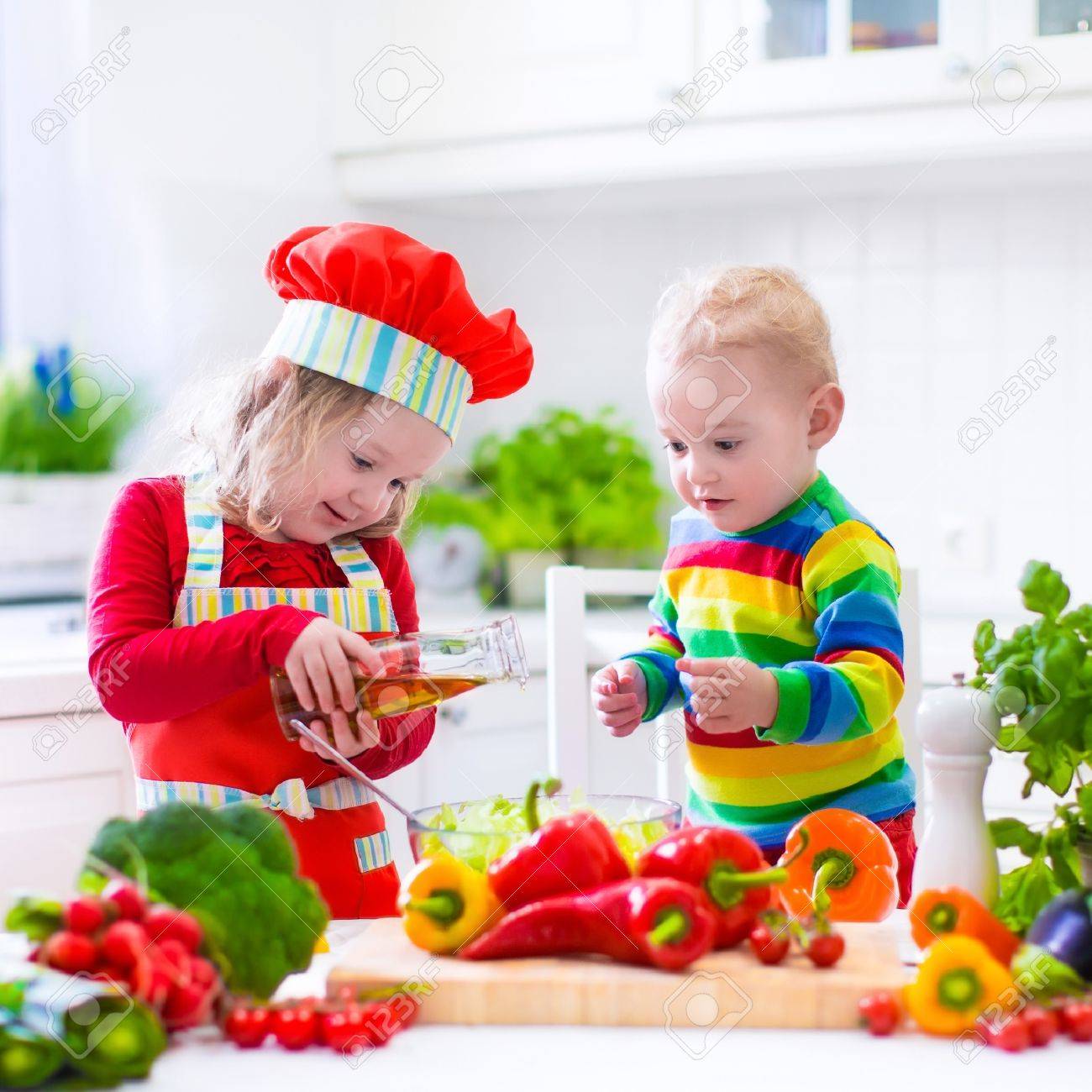 Deux Petits Enfants Fille Adorable Bebe En Chapeau De Chef Rouge Et Un Tablier Et Drole Garcon Preparation Repas Sain Faisant Delicieuse Salade Avec Des Legumes Frais Et Des Herbes Du Jardin