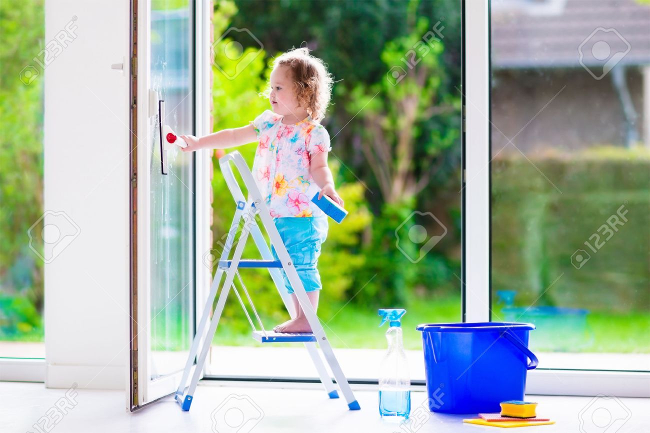 little girl washing a window kids clean the house children help cleaning house