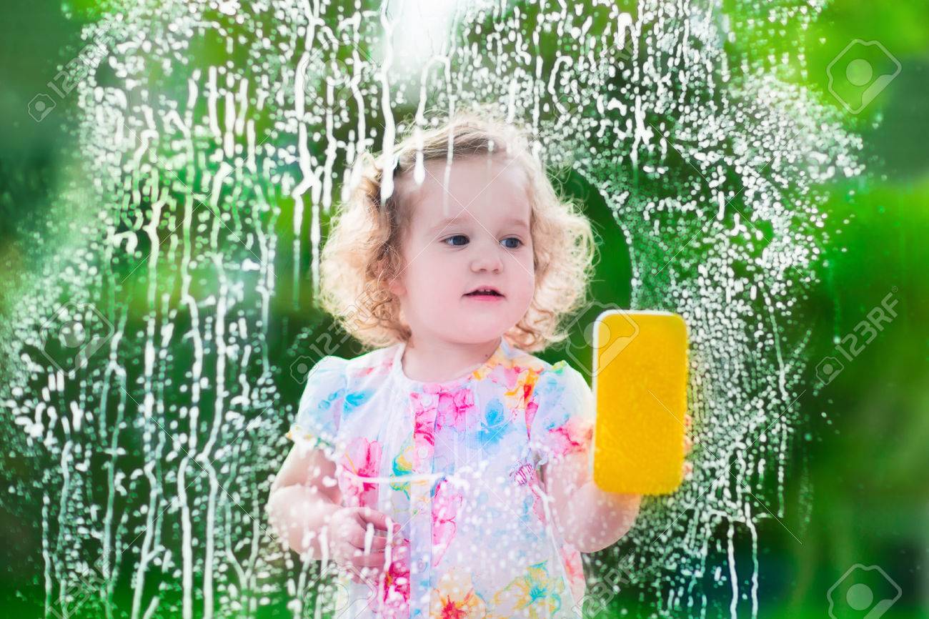 little girl washing a window kids clean the house children help cleaning house