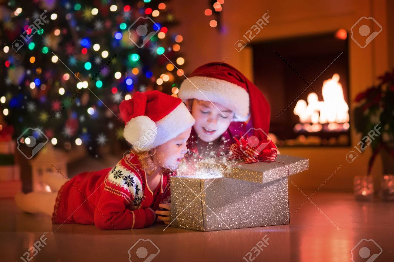 family on christmas eve at fireplace kids opening xmas presents children under christmas tree - Xmas Presents family on christmas eve at fireplace kids opening xmas presents children under christmas tree - Xmas Presents
