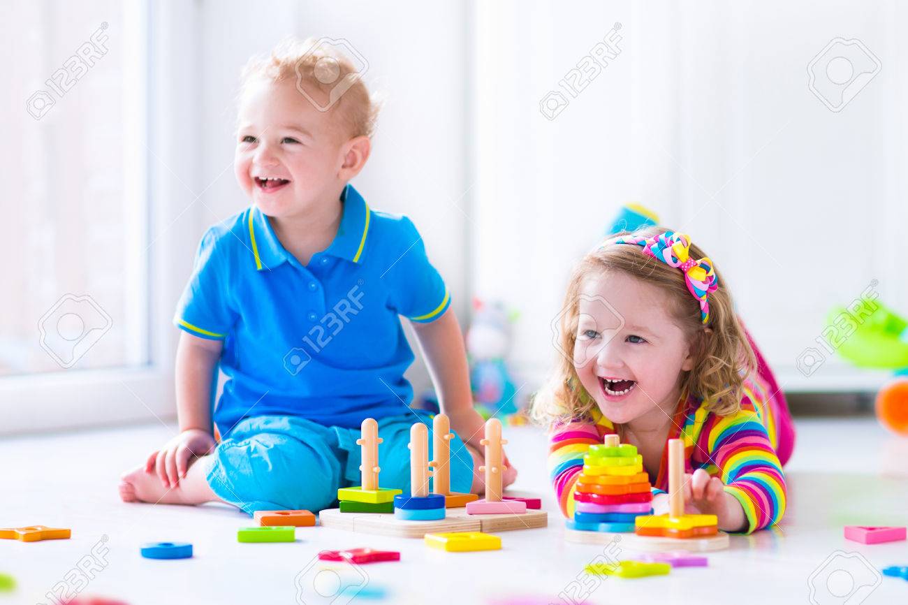木のおもちゃで遊ぶ子供たち 2 人の子供 かわいい幼児の女の子 面白い男の子は おもちゃ のブロックと自宅の塔を構築またはデイケアで遊んで 保育園と幼稚園の教育子供のおもちゃ の写真素材 画像素材 Image