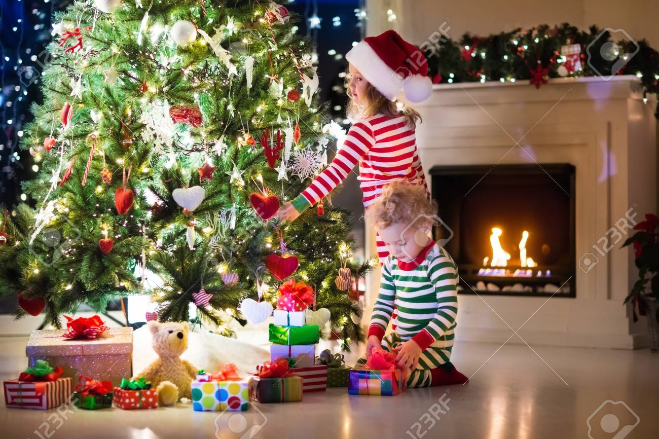 Bimbi Che Aprono I Regali Di Natale.Immagini Stock Felice Piu Piccoli In Corrispondenza Pigiama A Strisce Rosse E Verdi Decorare L Albero Di Natale In Bel Soggiorno Con Camino Tradizionale Bambini Che Aprono I Regali La Vigilia Di