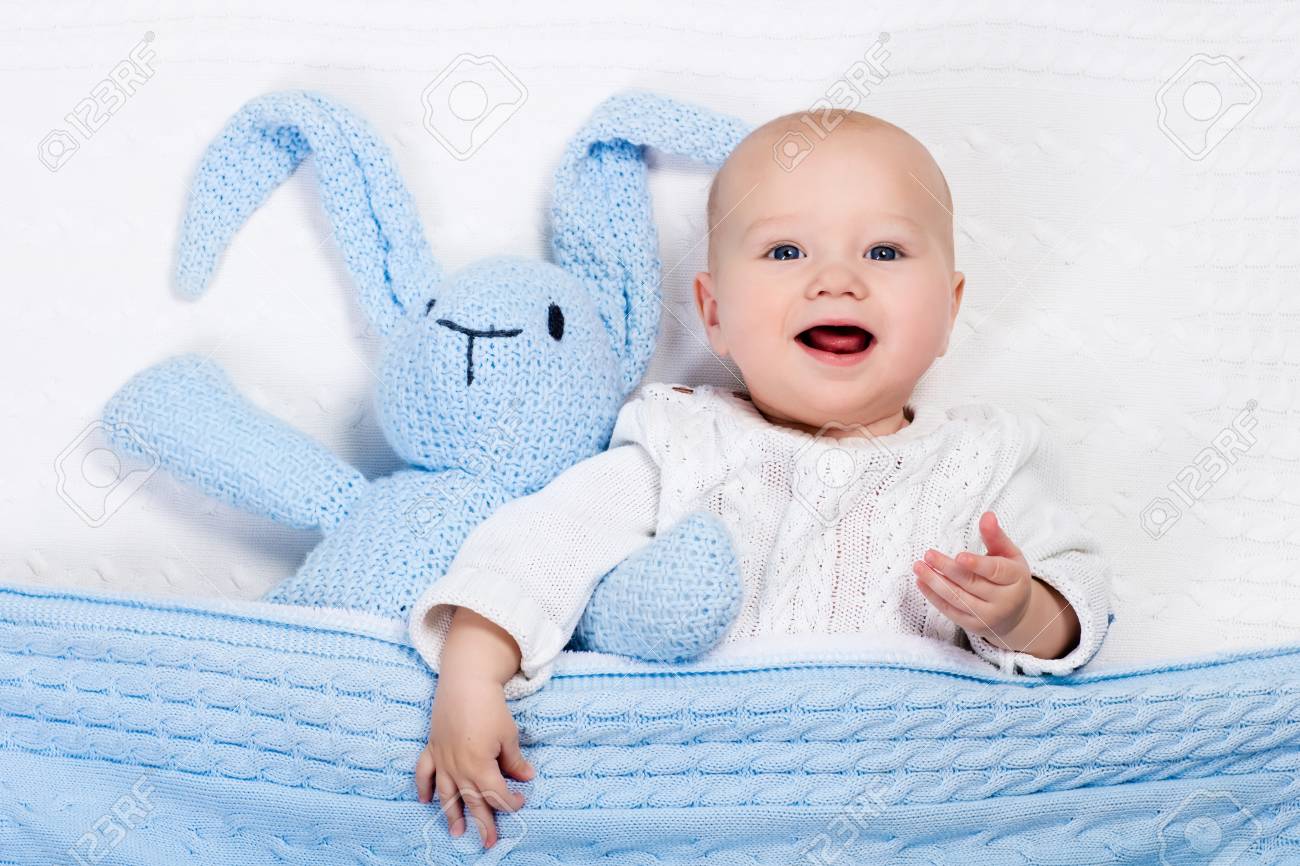 白いケーブルでリラックス グッズ ウサギと遊ぶ暖かいニットのジャケットを身に着けている面白い赤ちゃんニット日当たりの良い保育園の毛布です 子供たちの冬の衣類や寝具 子供のおもちゃや繊維のハンドメイド の写真素材 画像素材 Image