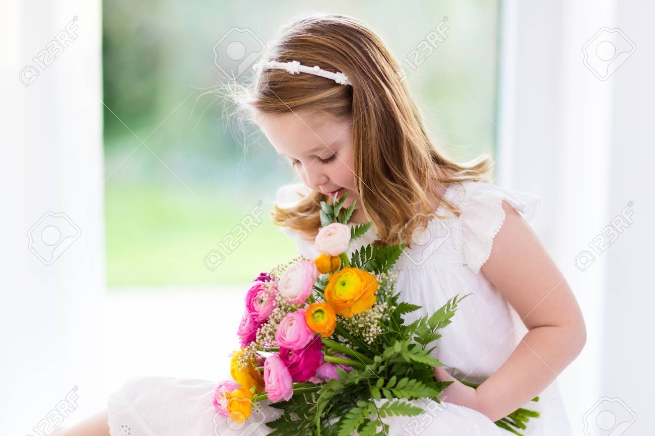 ラナンキュラスの花の花束の誕生日パーティーを保持している白いドレスでかわいい女の子 結婚式で小さな花の女の子 夏の花の子 お祝いの洗礼に春の花の子供します の写真素材 画像素材 Image