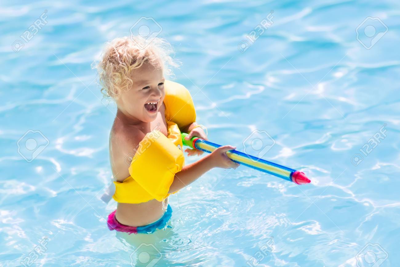 Heureux Enfant Rire En Jouant Avec Pistolet à Eau Dans La Piscine Extérieure En Vacances Dété Dans La Station Balnéaire Tropicale Les Enfants Jouent
